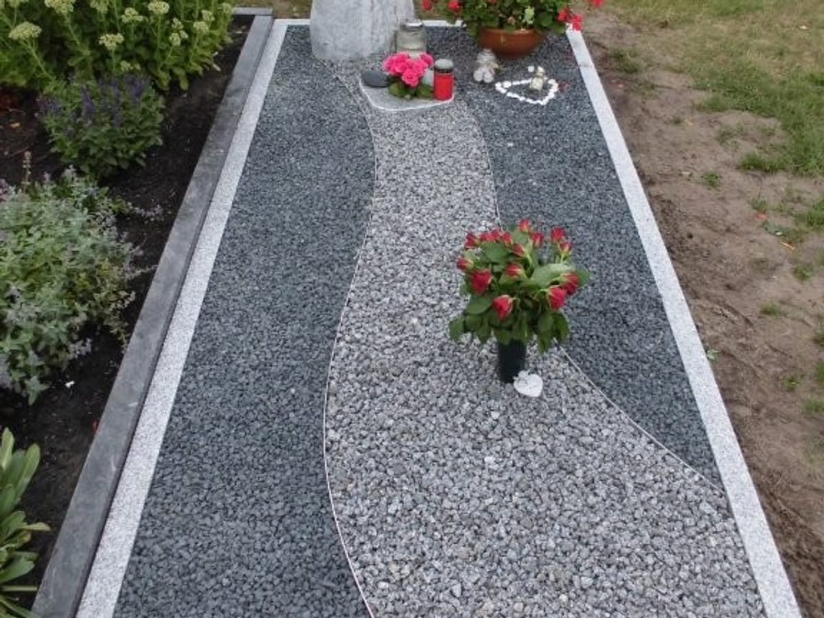 Grabstätte mit heller Granit-Einfassung, geschwungenem Kiesband und schlichter Stele